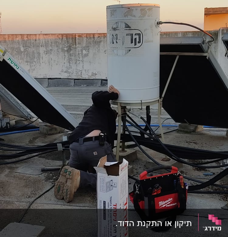 אדם מתקן דודי שמש על גג עם כלים.